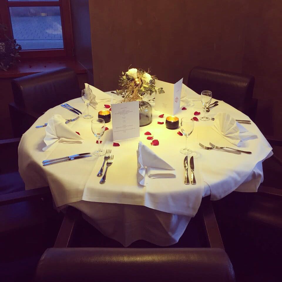 Romantischer Tisch für zwei mit Rosenblättern und Kerzenlicht
